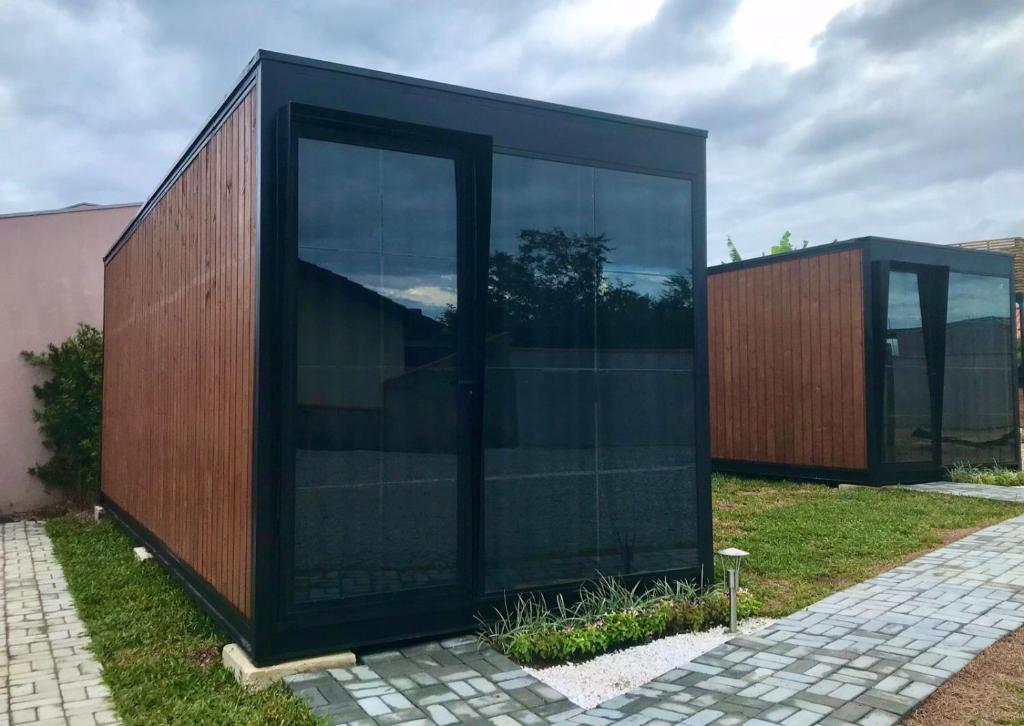 a black building with glass doors in a yard at Modo- lar mini casa in Penha