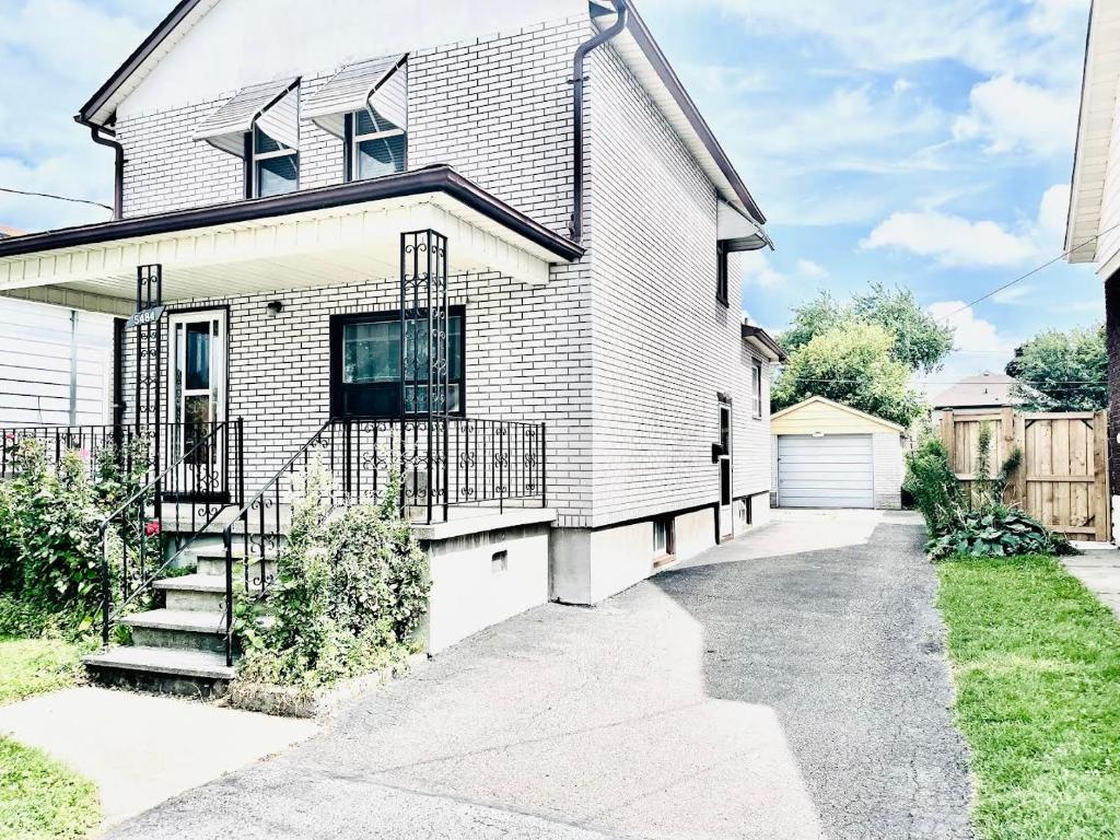 Falls House Downtown Niagara Falls Canada في شلالات نياجارا: منزل من الطوب الأبيض مع ممر