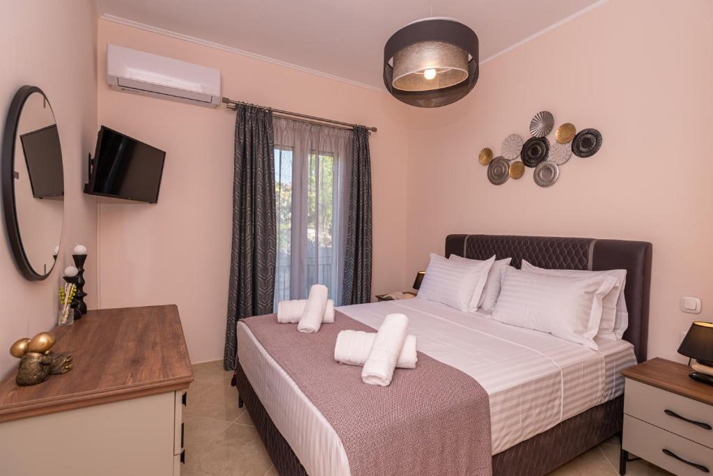 Schlafzimmer mit einem Bett mit weißer Bettwäsche und einem TV in der Unterkunft Zoes Luxury Apartment Corfu in Ágios Rókkos