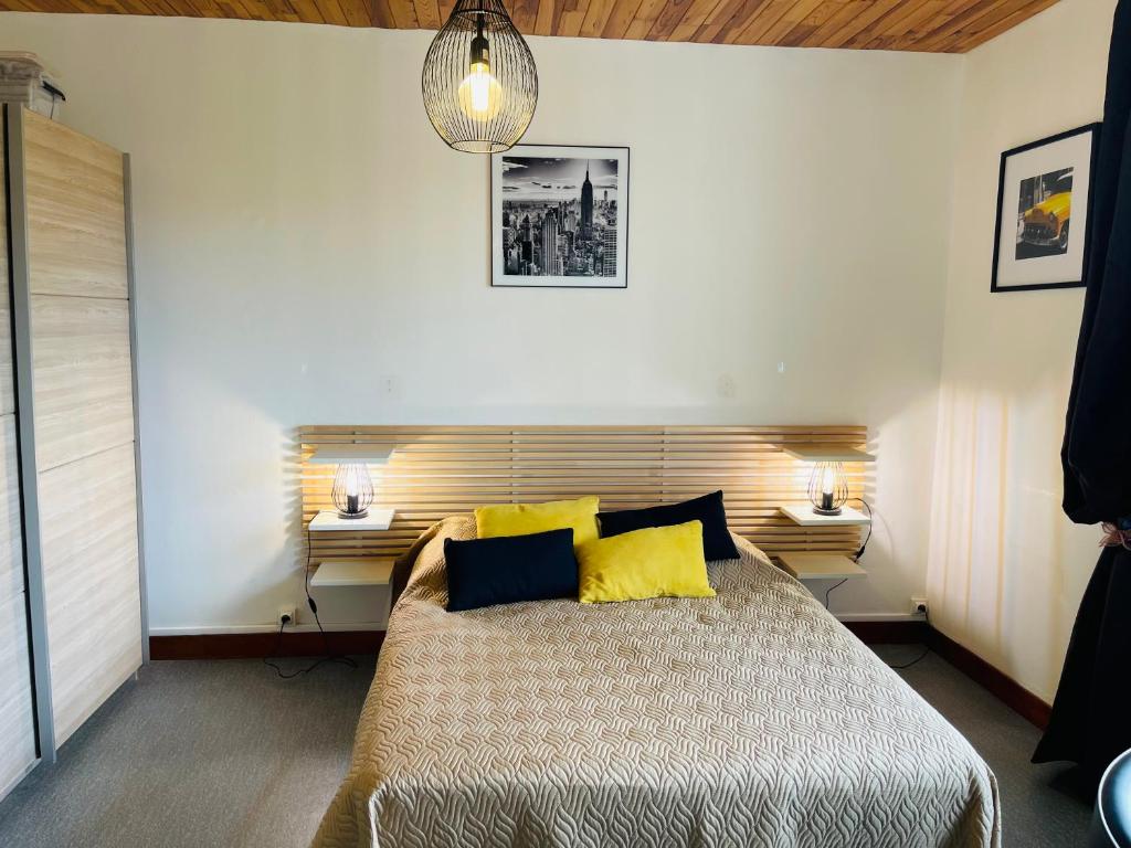 1 dormitorio con 1 cama grande con almohadas amarillas en Studio COSY avec parking et wifi gratuit, en Bagnoles de l'Orne