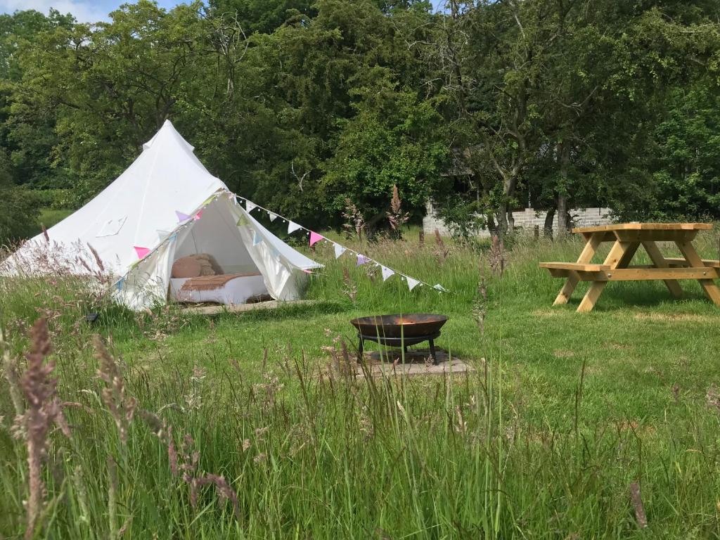 Tienda blanca en un campo con mesa de picnic en Panpwnton Farm Bell Tents, en Knighton