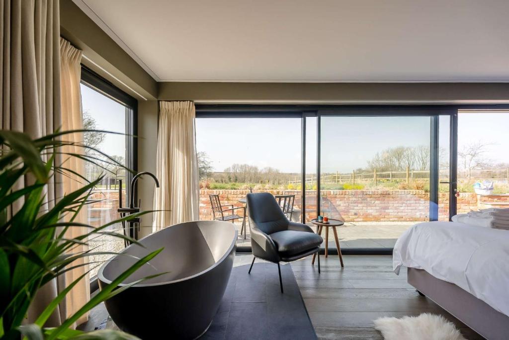 a bedroom with a bed and a chair and a large window at Little Hayloft by Bloom Stays in Canterbury