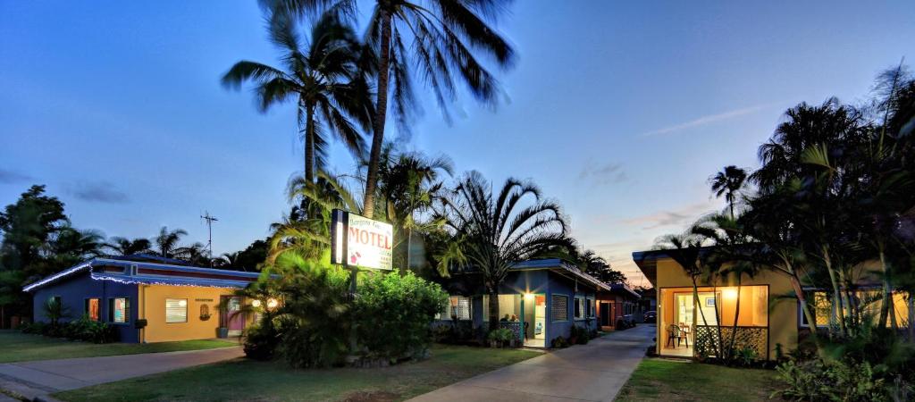 a large house with trees and palm trees at Bargara Gardens Boutique Villas in Bargara
