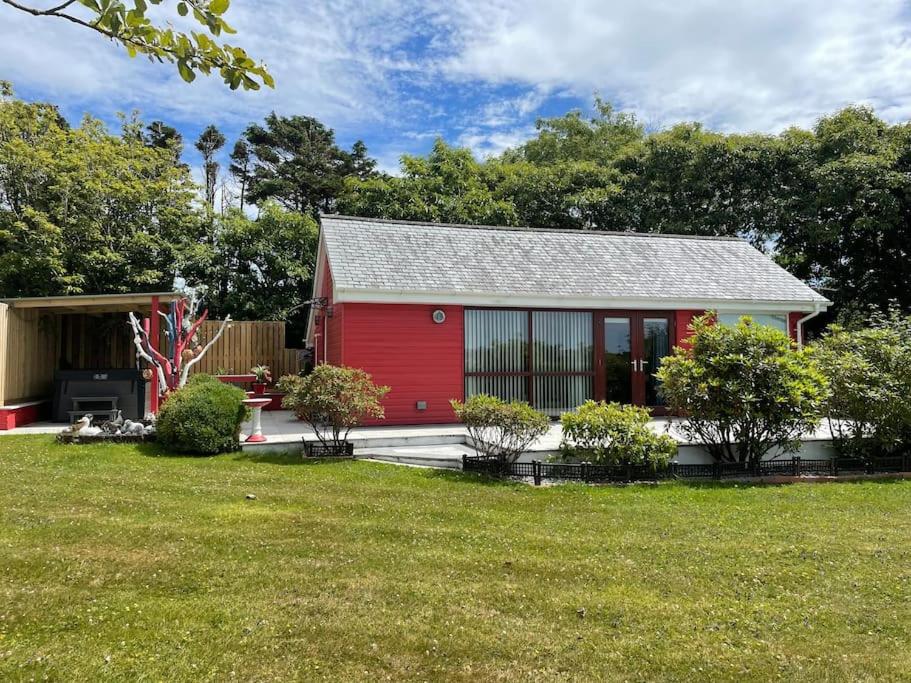 uma casa vermelha com uma porta vermelha num quintal em Meadowside Lodge with Hot Tub em Truro