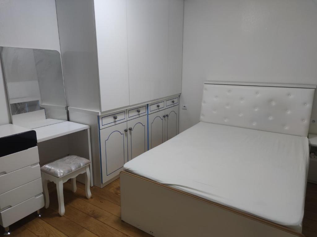 a small white bedroom with a bed and a stool at Chambre privée à Bobigny -salle de bain et toilettes sont commune, -pas de cuisine in Bobigny