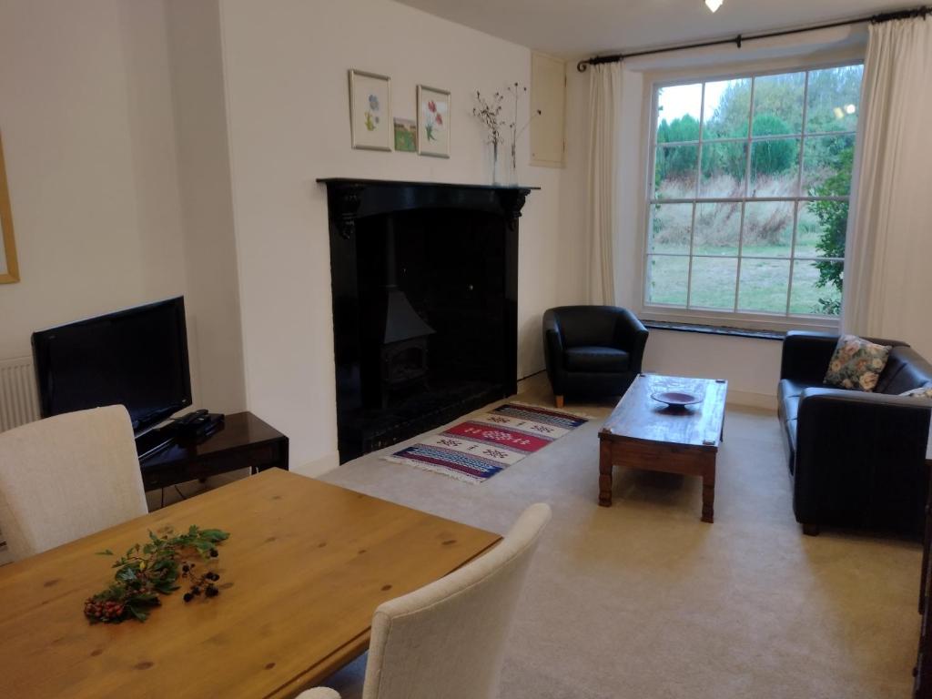 a living room with a table and a fireplace at Headson Farmhouse in Bratton Clovelly