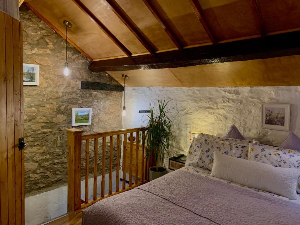 um quarto com uma cama e uma parede de pedra em Old Nursery em Coity