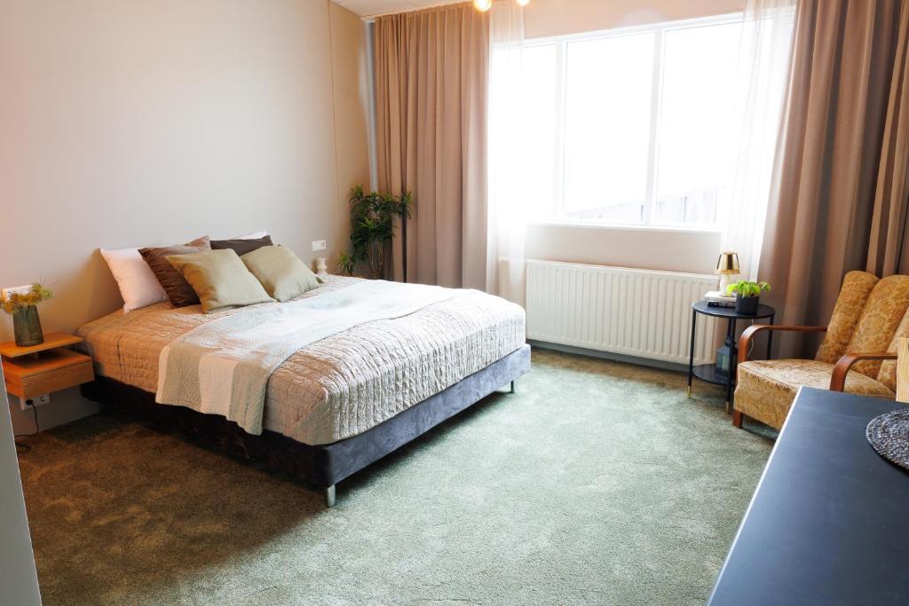 een slaapkamer met een bed en een groot raam bij Hotel Kaldi in Litli-Árskógssandur
