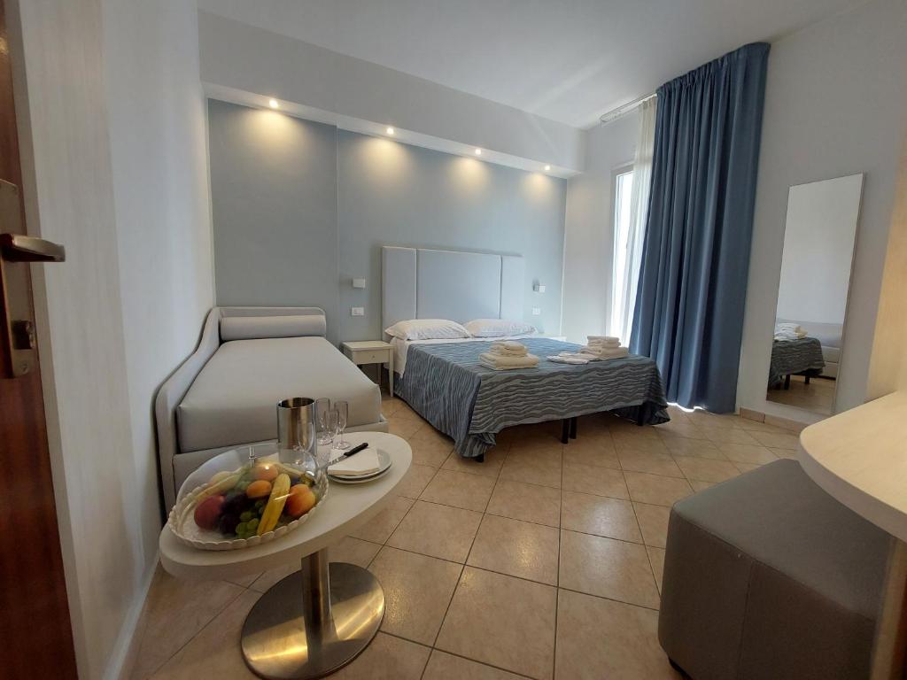 Cette chambre comprend un lit et une table avec des fruits. dans l'établissement Hotel Caravel Park, à Rimini