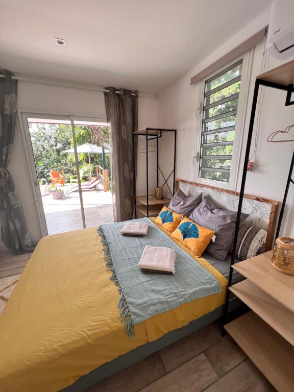 a bedroom with a bed and a large window at Les Vanniers: Papaye - KARITÉ in Baie-Mahault