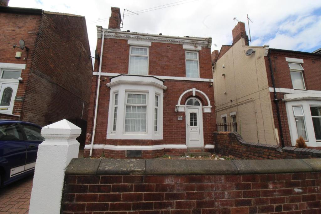 a red brick house with a white door at St Ann's House in Rotherham