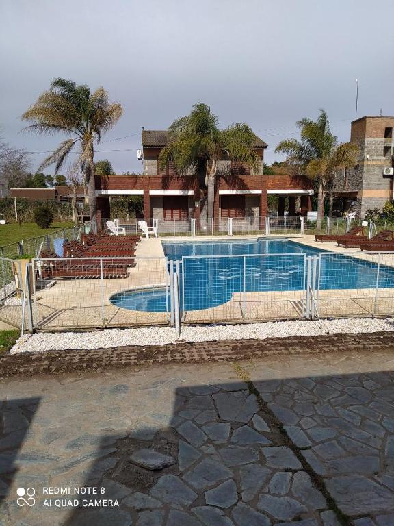 a swimming pool in front of a building at Mediterráneo Cabañas in Chascomús