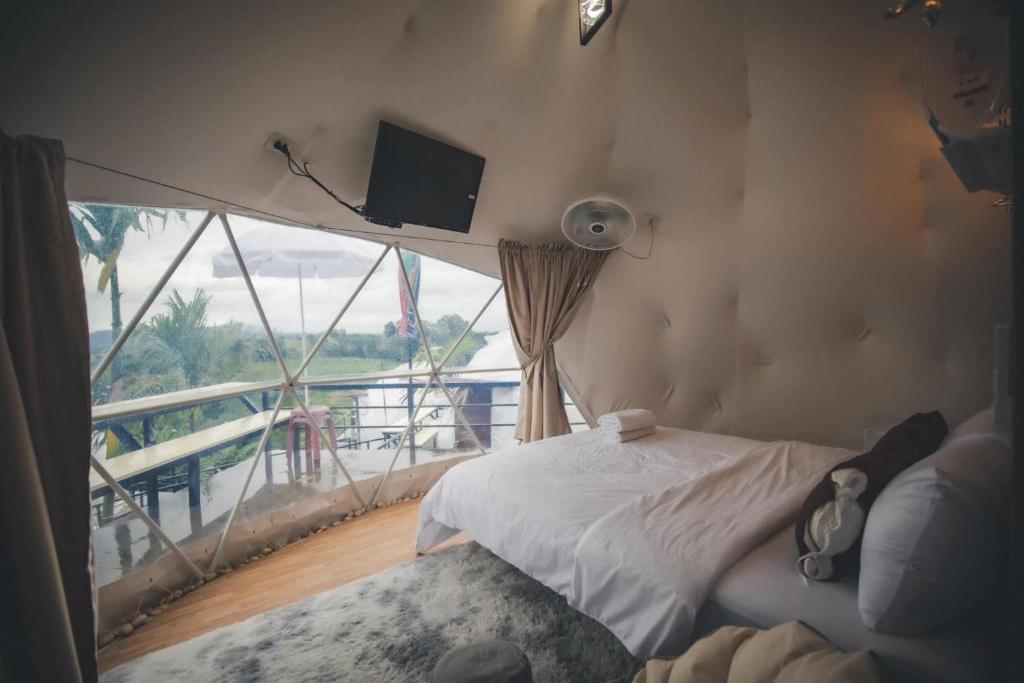 um quarto com uma cama e uma grande janela em นรดีฮิวล์ รีสอร์ต เขาแผงม้า วังน้ำเขียว em Ban Sap Bon