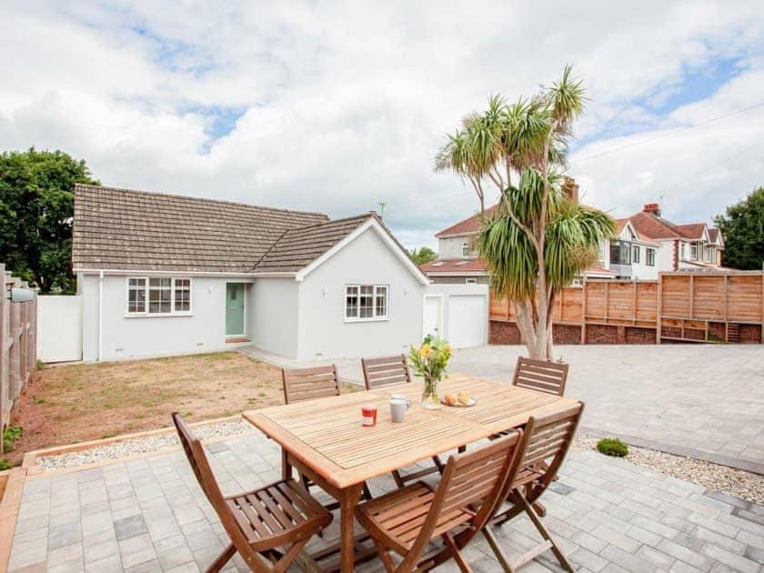 a patio with a wooden table and chairs at HONEYBROOK - Cosey detached home, modern, spacious in Torquay