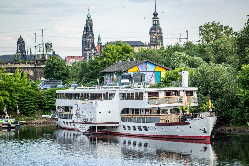 un barco en el agua con un edificio en la parte superior en Schiffsherberge Pöppelmann, en Dresden