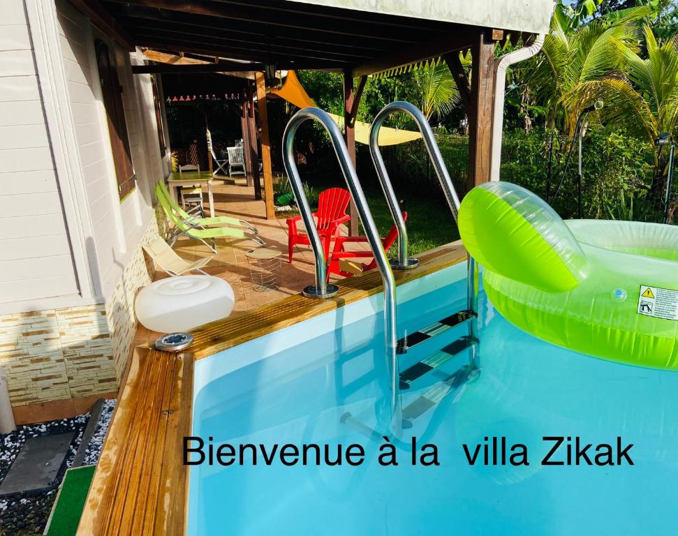 einen Pool mit einer grünen aufblasbaren Badewanne in einem Haus in der Unterkunft Magnifique Lodge en bois avec piscine et jardin de 800 m2 in Le Lamentin