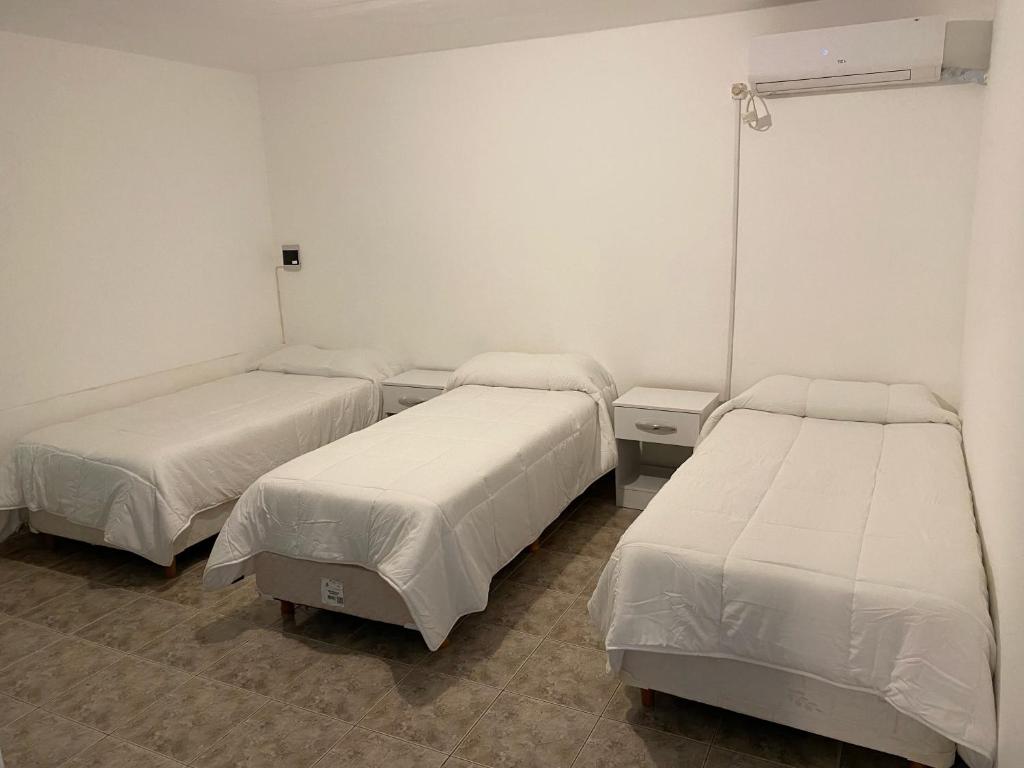 3 camas en una habitación con paredes blancas en ALOJAMIENTO ONCATIVO en Oncativo