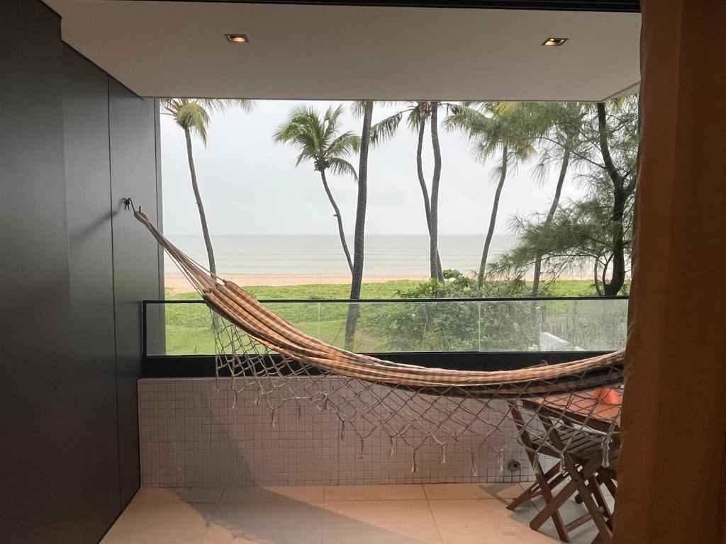 a hammock in a room with a view of the beach at Altamare - Pé na areia in Tambaú