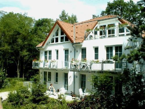 ein großes weißes Haus mit Balkon mit Menschen darauf in der Unterkunft Waldhaus Mühlenbeck bei Berlin in Mühlenbeck