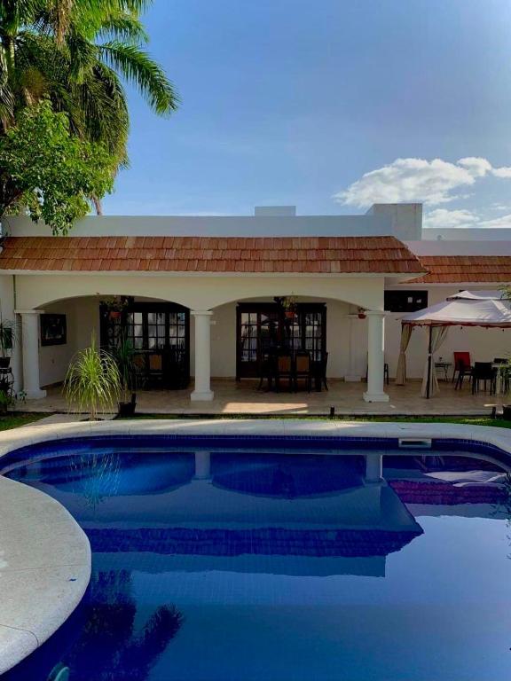 a house with a swimming pool in front of a building at Hotel Boutique Villas Segovia Cozumel in Cozumel