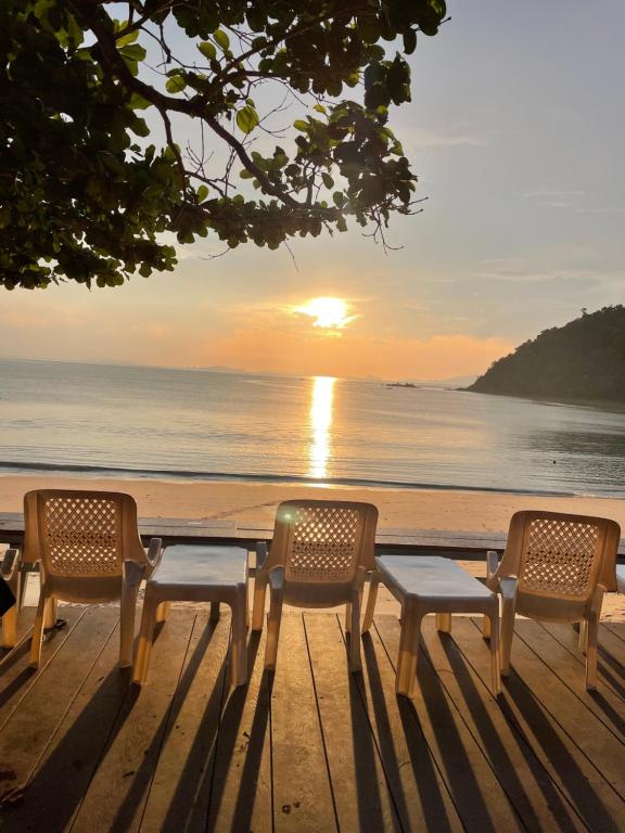 Marina Resort Koh Phayam Ranong في كو فايام: طاولة وكراسي على الشاطئ مع غروب الشمس