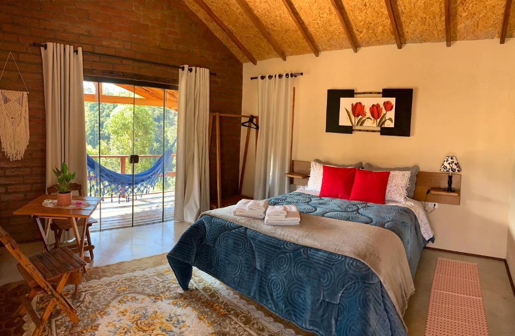 - une chambre avec un lit doté d'oreillers rouges et une fenêtre dans l'établissement Chalés Água azul, à Santo Antônio do Pinhal