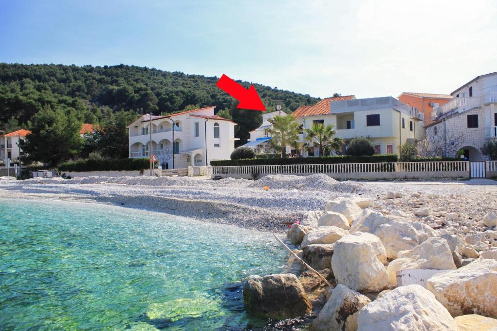 a red arrow on a rocky beach with houses at Apartments by the sea Slatine, Ciovo - 1098 in Slatine