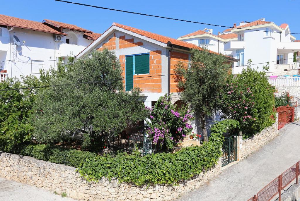 una pared de piedra con árboles y flores frente a una casa en Apartments by the sea Okrug Gornji, Ciovo - 1111 en Trogir