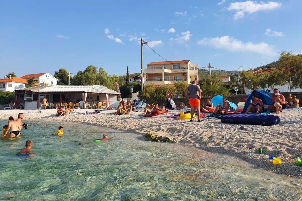 un grupo de personas en el agua en una playa en Apartment Arbanija 1122a en Trogir