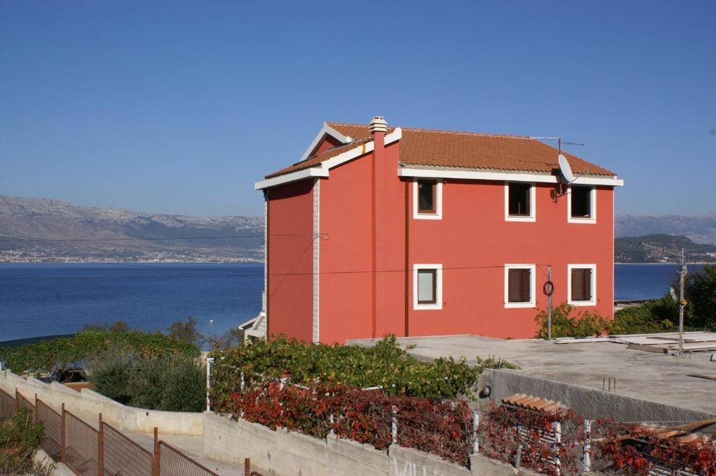 a red building next to a body of water at Apartment Slatine 1128a in Slatine