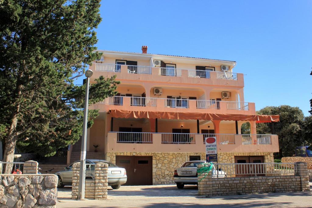 a large orange building with cars parked in front of it at Apartments and rooms by the sea Mandre, Pag - 3557 in Kolan