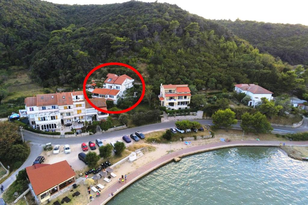 een huis met een rode cirkel eromheen naast het water bij Studio Supetarska Draga - Donja 2022b in Rab