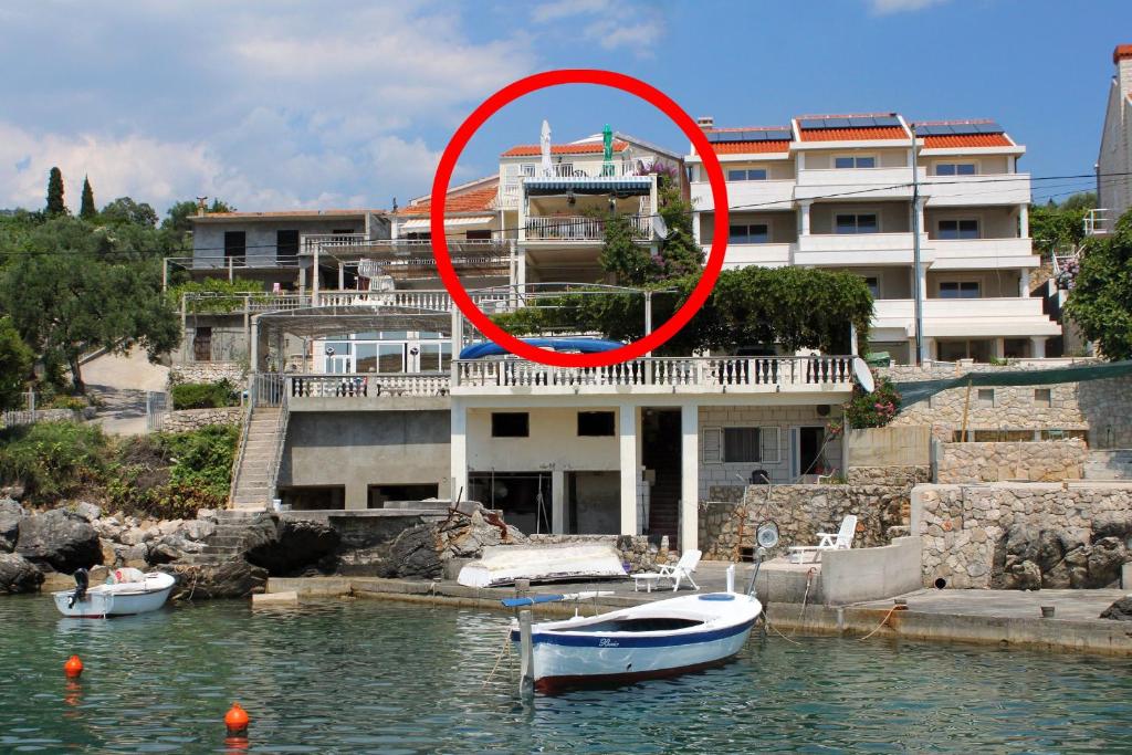 a house with a boat in the water in front of it at Apartments by the sea Molunat, Dubrovnik - 2137 in Molunat