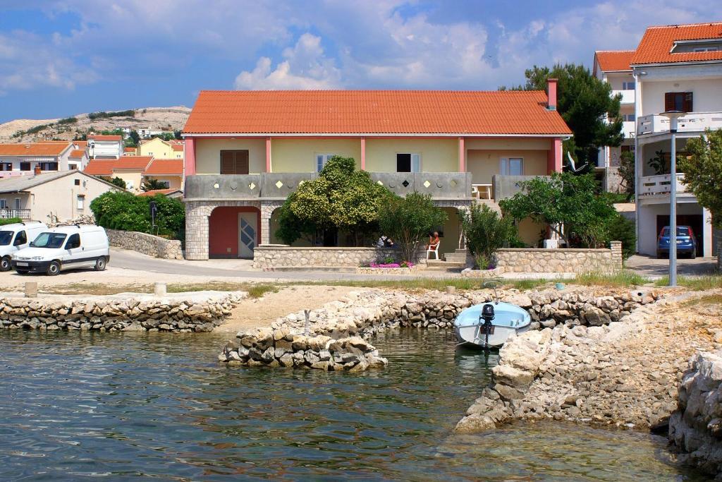 a boat in the water in front of a house at Apartments by the sea Kustici, Pag - 4081 in Zubovići