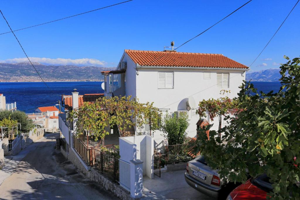 a white house with a car parked in front of it at Apartments with a parking space Slatine, Ciovo - 2030 in Trogir