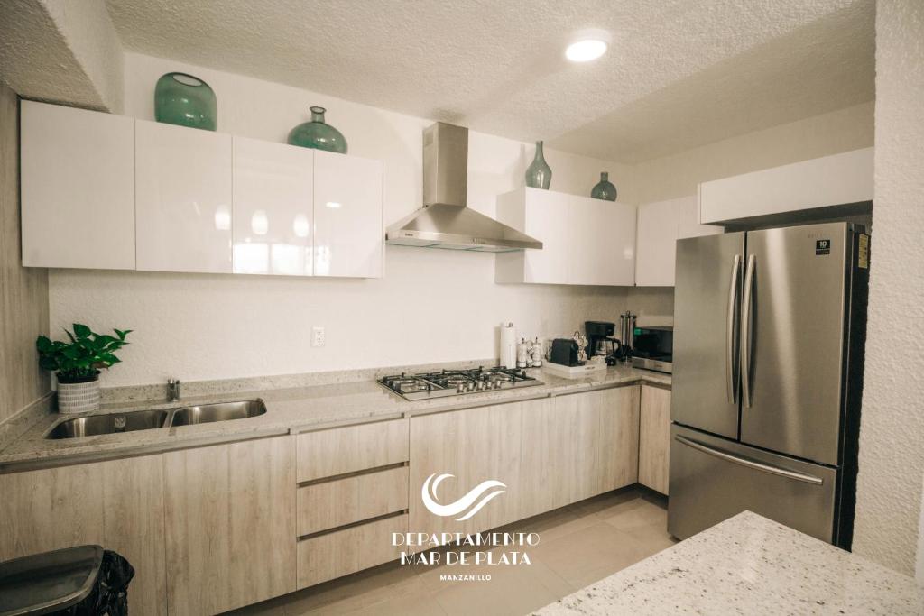 a kitchen with white cabinets and a stainless steel refrigerator at Hermoso Departamento Nuevo a 50 metros de playa!! in Manzanillo