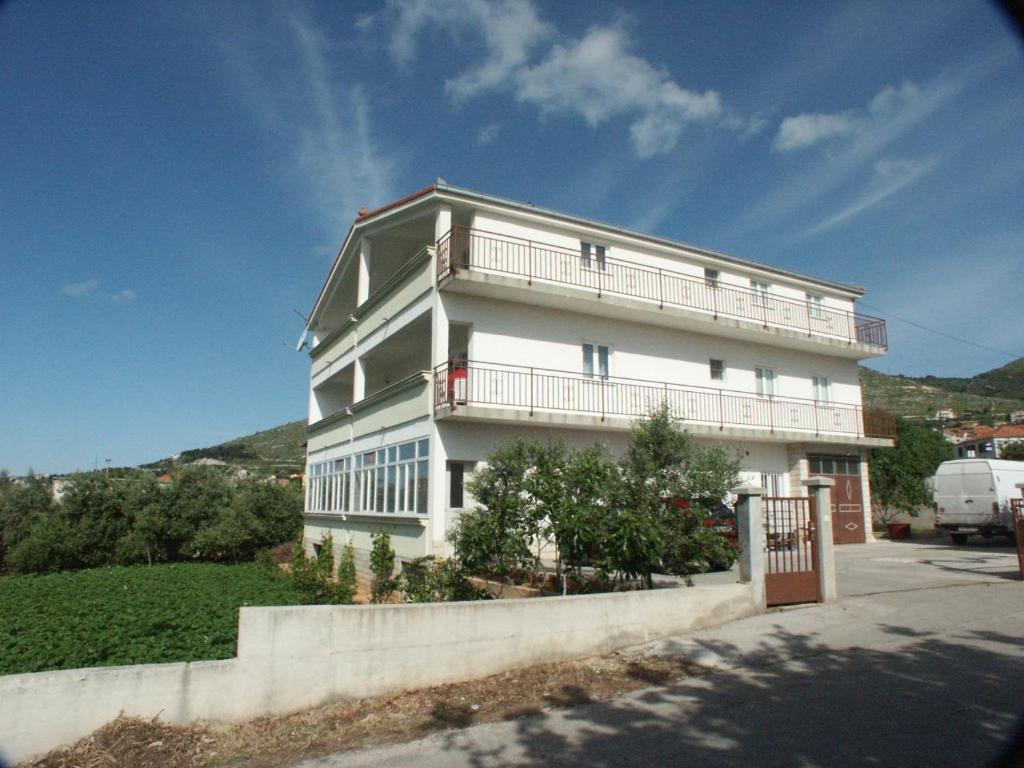 ein großes weißes Gebäude mit Balkon auf einer Straße in der Unterkunft Apartments by the sea Seget Donji, Trogir - 2041 in Trogir