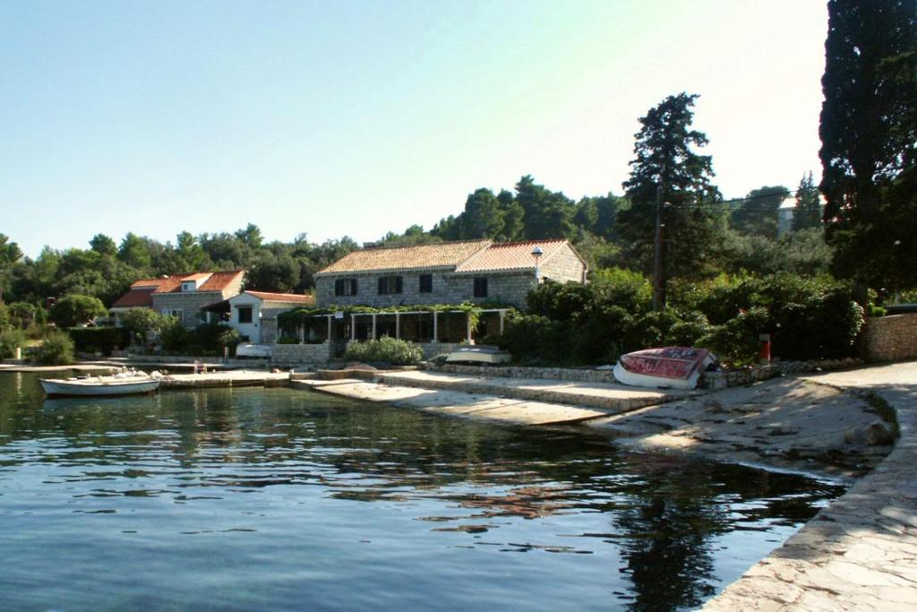 a house and boats in a body of water at Apartments and rooms by the sea Zaton Veliki, Dubrovnik - 2110 in Zaton