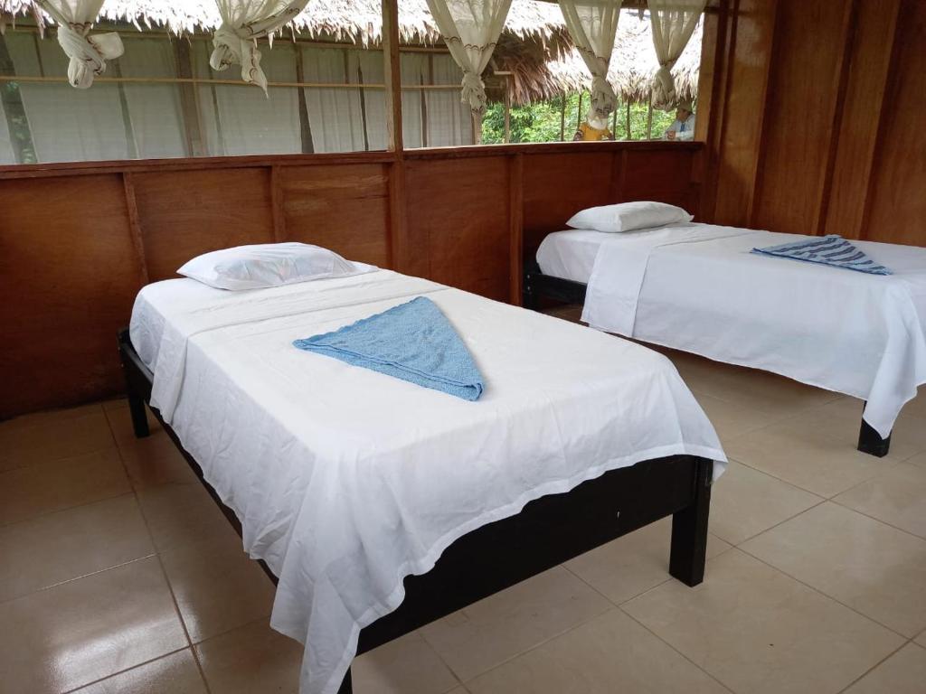 two beds in a room with white sheets at Golden waters Lodges in Iquitos