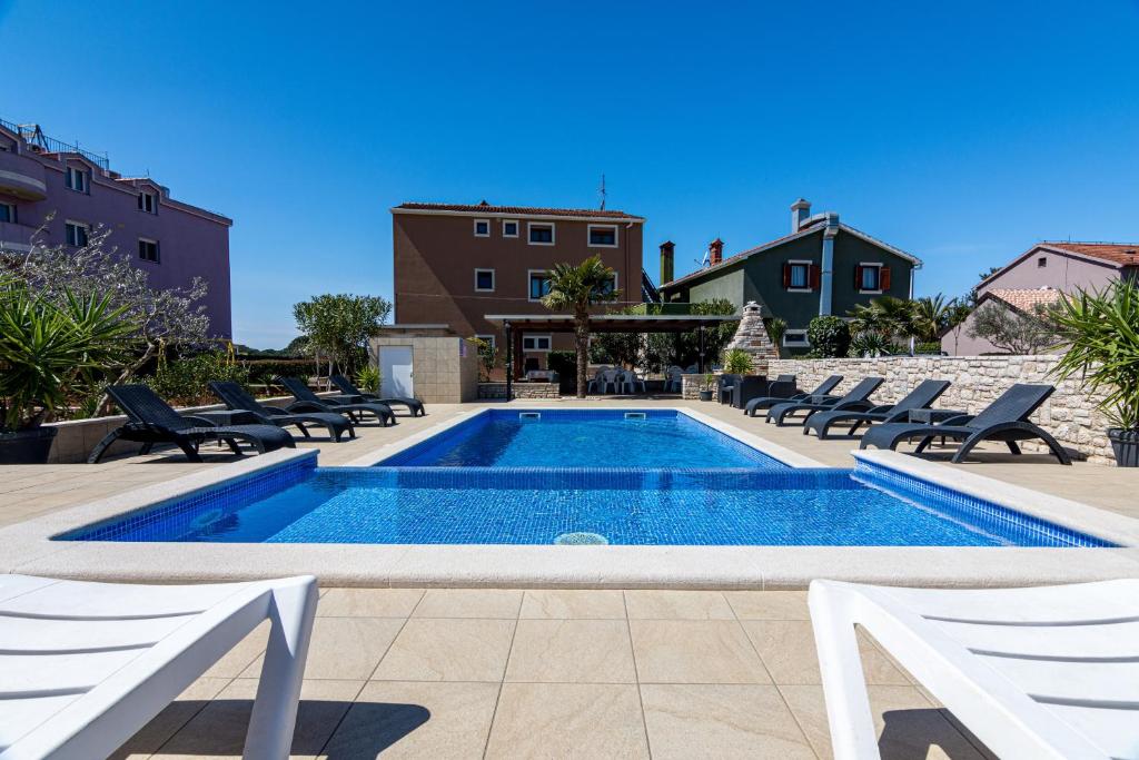 a swimming pool with lounge chairs next to a building at Family friendly apartments with a swimming pool Valbandon, Fazana - 2201 in Štinjan