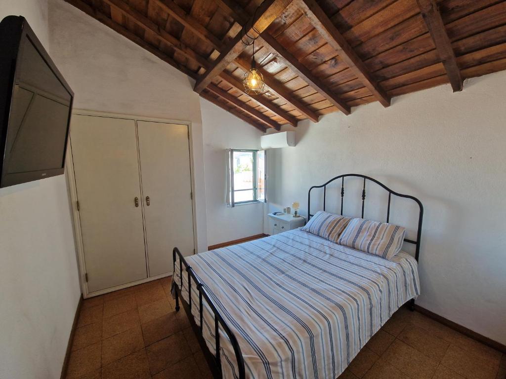 - une chambre avec un lit et une couverture rayée dans l'établissement T1 Centro Montargil, à Montargil