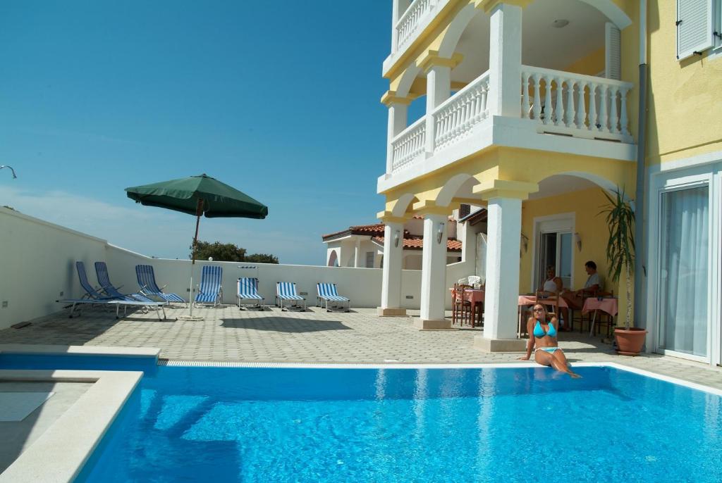 a child sitting in a swimming pool next to a house at Rooms with a swimming pool Peroj, Fazana - 2235 in Peroj