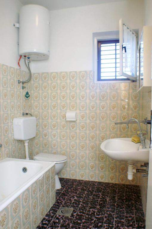 łazienka z umywalką, wanną i toaletą w obiekcie Family friendly seaside apartments Vlasici, Pag - 4131 w mieście Vlašići