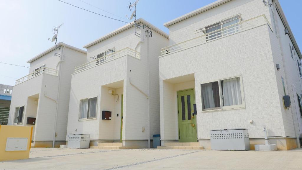 a white building with a green door at グランディオーソ沖縄ヴィラ恩納5 in Onna