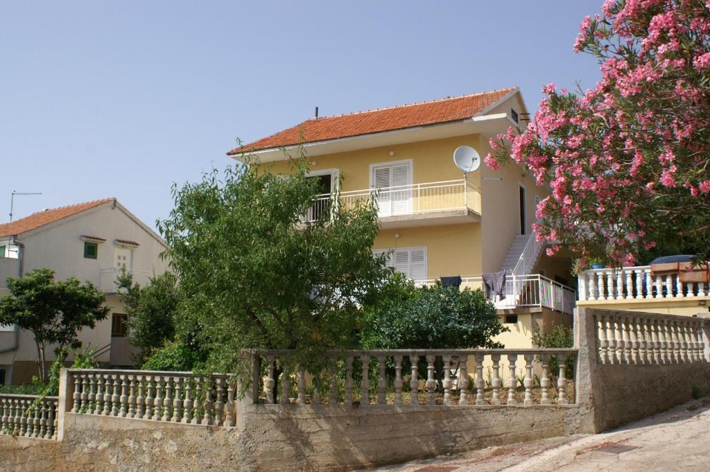 ein gelbes Haus mit einem Zaun und rosa Blumen in der Unterkunft Apartment Grebastica 4207b in Bašelovići