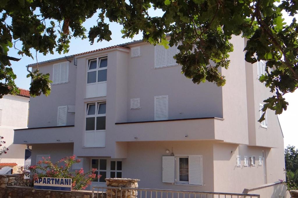 ein großes weißes Gebäude mit weißen Fensterläden in der Unterkunft Apartments with a parking space Potocnica, Pag - 4096 in Stara Novalja