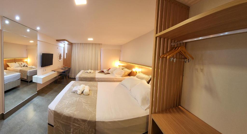 um quarto de hotel com duas camas e uma televisão em Flat Maravilhoso na praia - Ilusion Hotel em Natal