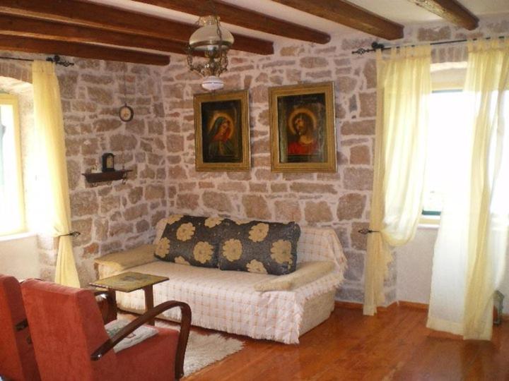 ein Wohnzimmer mit einem Sofa und einer Steinmauer in der Unterkunft Apartments by the sea Sepurine, Prvic - 4237 in Prvić Šepurine