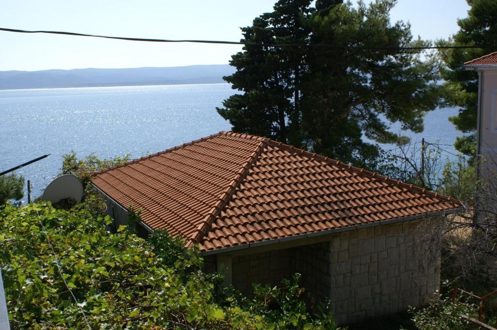 un edificio con techo de baldosas junto al agua en Seaside holiday house Pisak, Omis - 4280 en Pisak