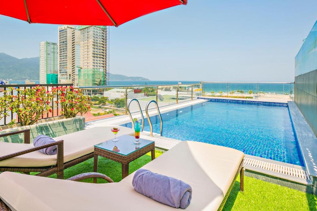 a pool on the roof of a building with chairs and an umbrella at Haka Boutique Hotel in Danang